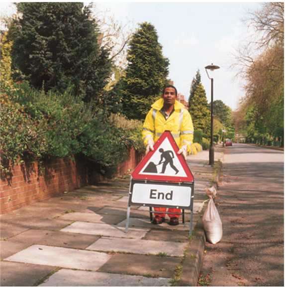 Man placing 'End of Roadworks' sign